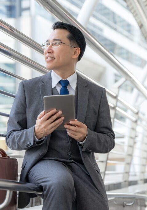 Portrait asian business man business district ,senior visionary executives leader with business vision , tabled phone computer in hand - lifestyle business people concept